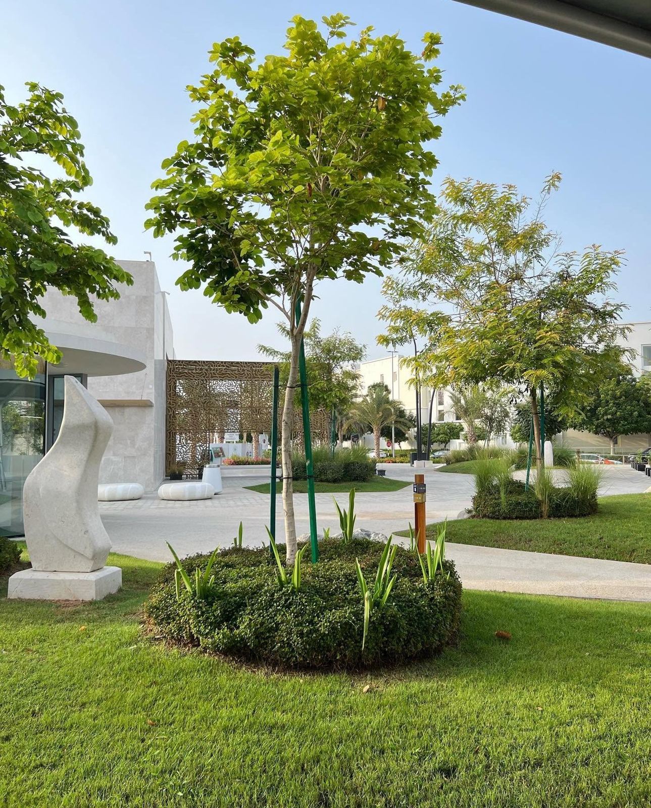 Landscaped courtyard with lawn, shrubs and a stone sculpture in Oman