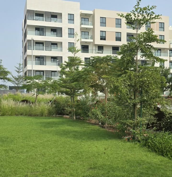 Mature trees and lawn in front of a residential building in Muscat